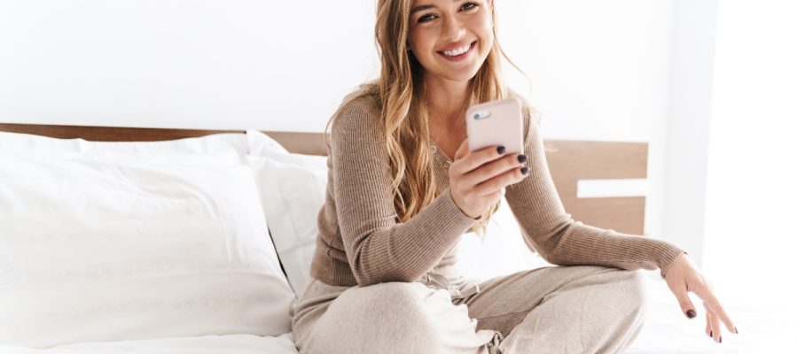 une femme souriant devant son téléphone