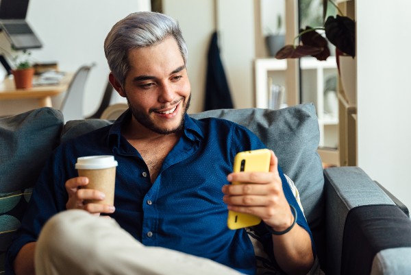 un homme souriant devant son téléphone 
